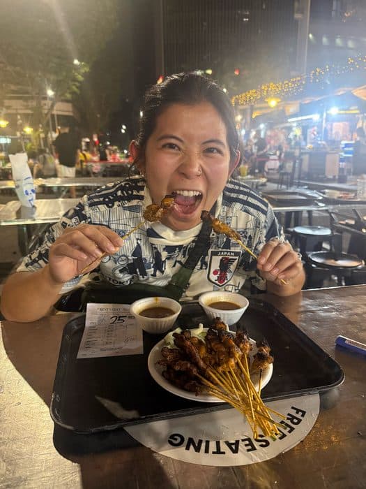 Jenny with a plate of satay skewers at a hawker stall