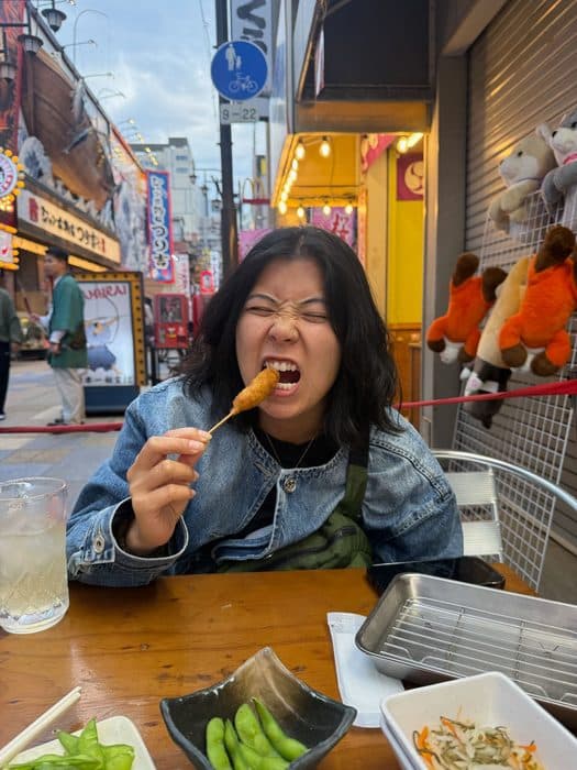 Jenny eating kushikatsu on a street in Osaka