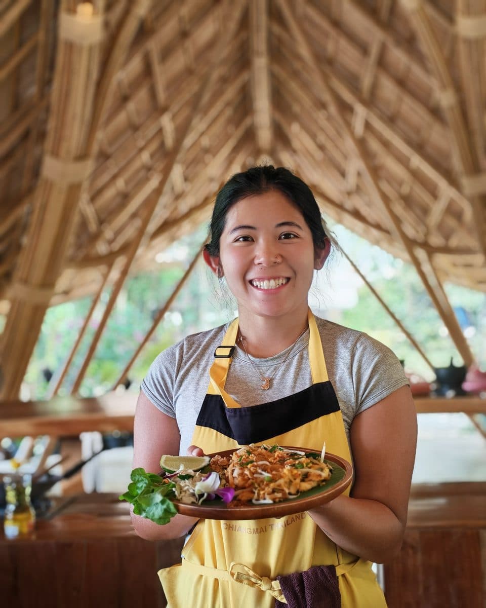 Jenny in an apron holding a plated dish she cooked
