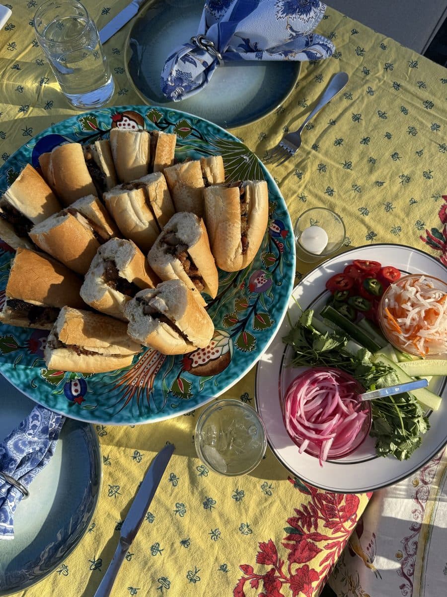 Bánh mì on a painted platter with pickled vegetables, herbs and chilies